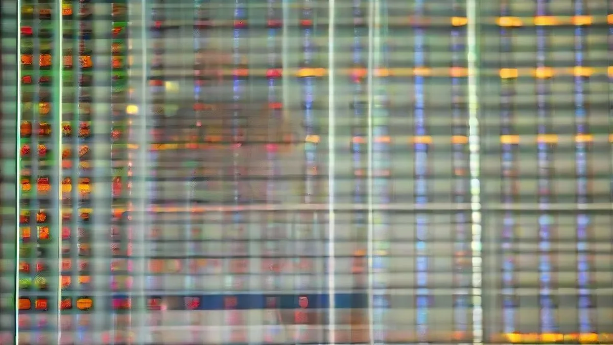 A financial trader monitoring monitors on an exchange floor with a concentrated expression.