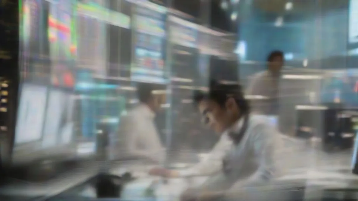 Financial analyst working late at desk with monitors reviewing market data