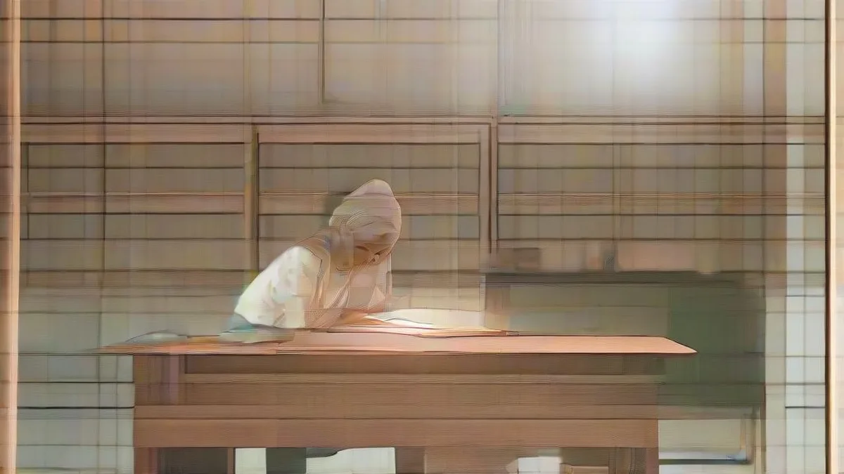 A young female student studying with books and a laptop in soft morning light.