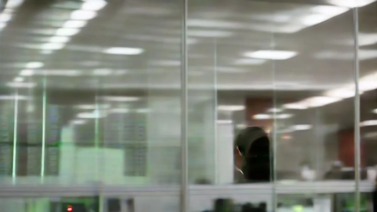 A financial trader analyzing market data on multiple computer displays in an office.