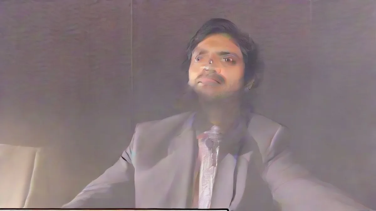 An Indian male music artist speaking somberly into press microphones at an indoor media conference.