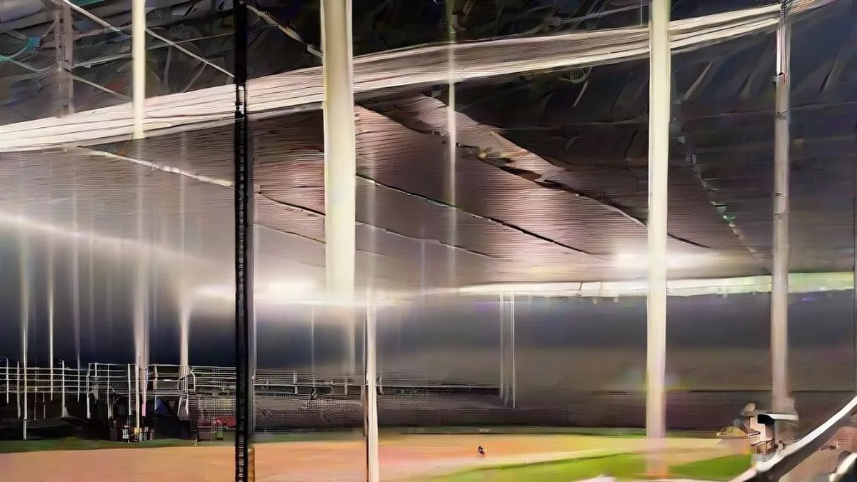 Large concert stadium stage and lighting rigs being prepared at dusk by ground crew