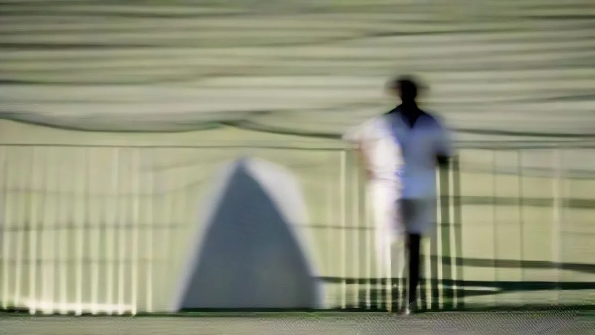 Cricketer Glenn Phillips walking off the pitch under floodlights after an international match