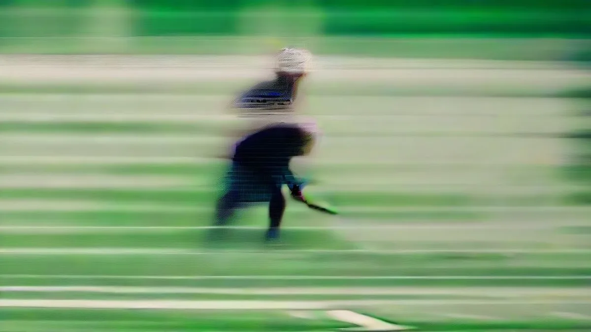 Field hockey player maneuvering the ball on a wet turf under stadium lights