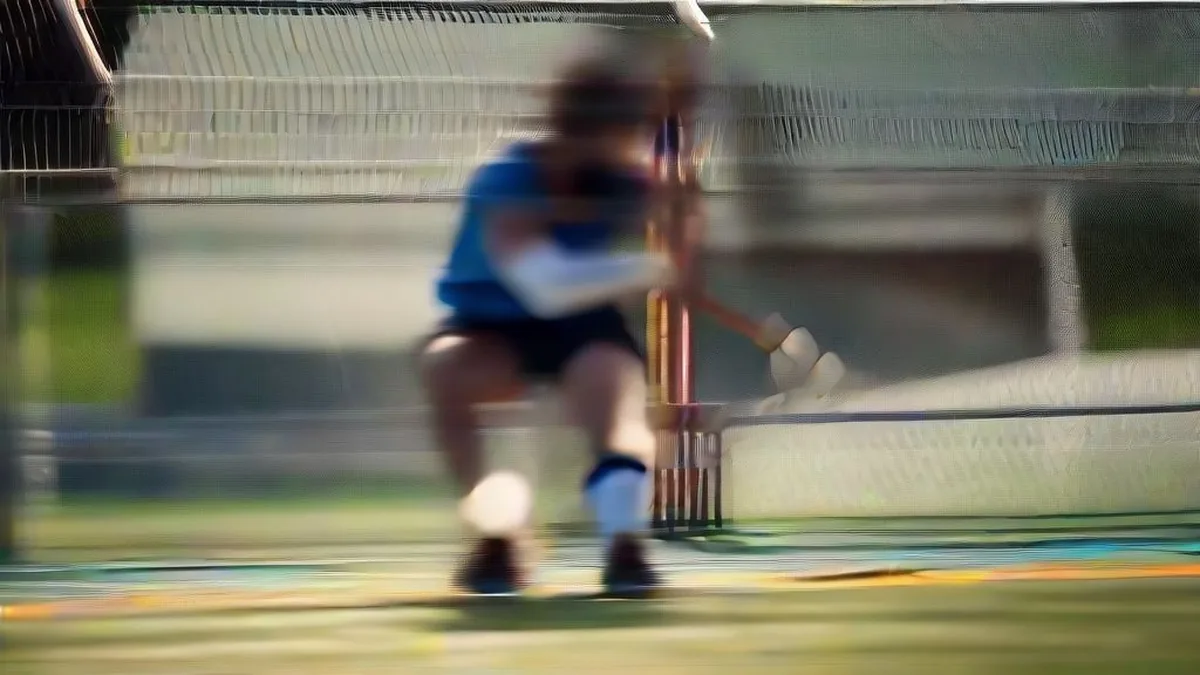 Indian field hockey player holding a hockey stick while seated by the turf during training