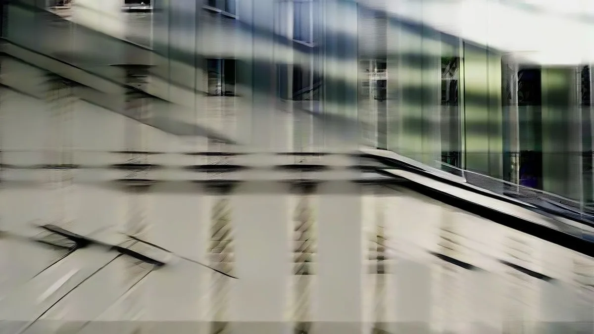 A worker walking outside a modern corporate building on an overcast day representing tech layoffs