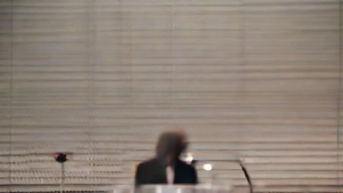 A corporate executive speaking at a conference podium under stage lighting