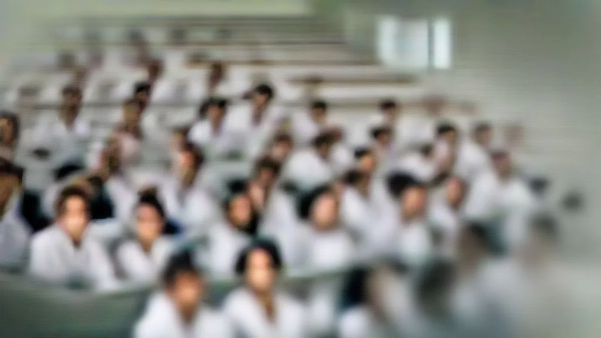 Medical students in white coats sitting in a modern lecture hall during a clinical class