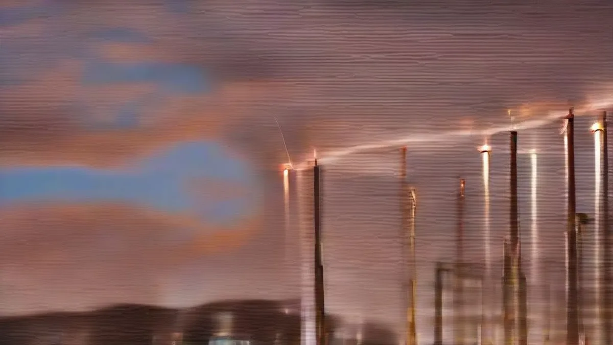 Industrial oil refinery towers and storage tanks during sunset with atmospheric steam and evening sky