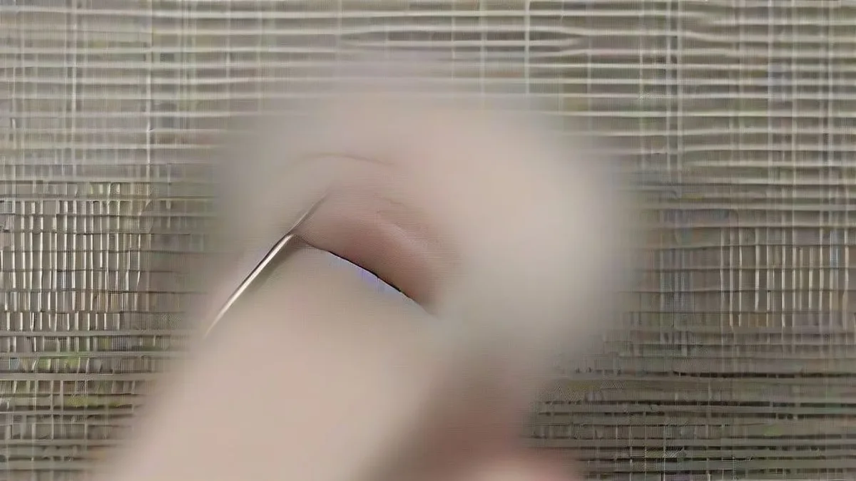 A minimalist titanium smart ring worn on an index finger resting on a wooden surface.