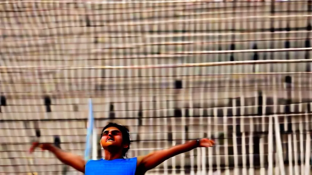 Indian para-athlete celebrating with arms raised under stadium floodlights