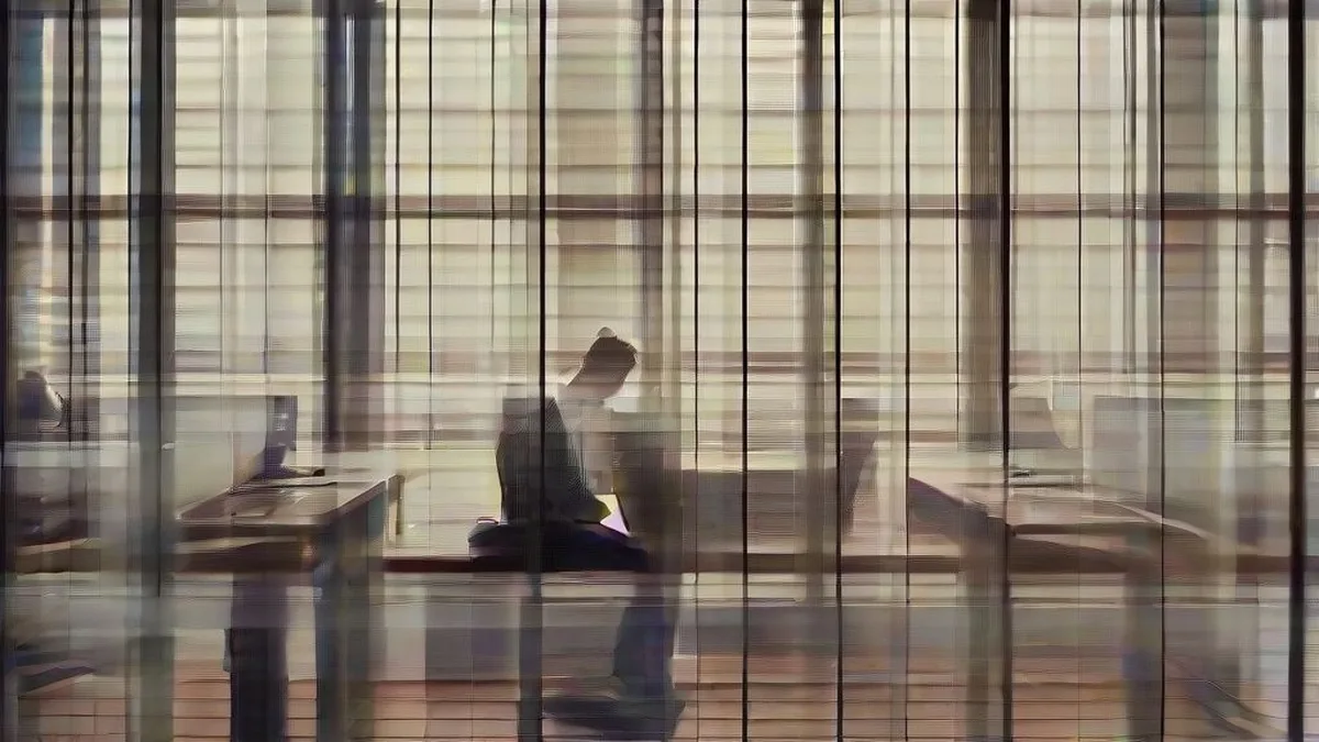 A software engineer working at a computer desk looking at lines of code across multiple monitors