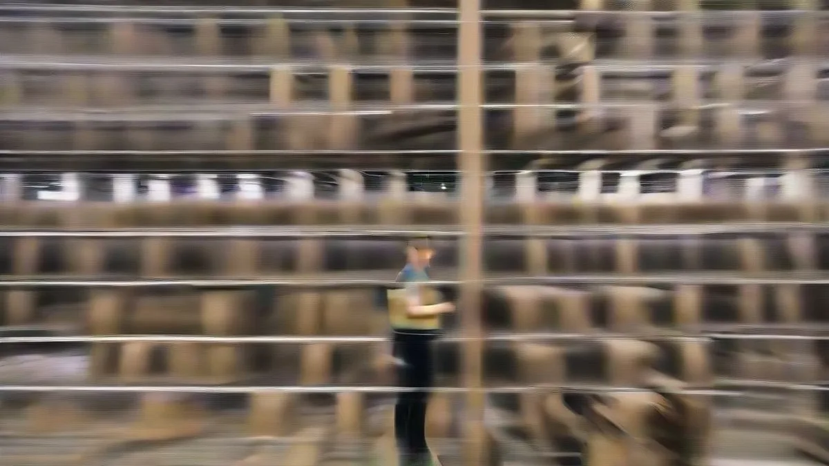 A warehouse manager inspecting inventory pallets in an expansive modern distribution center.