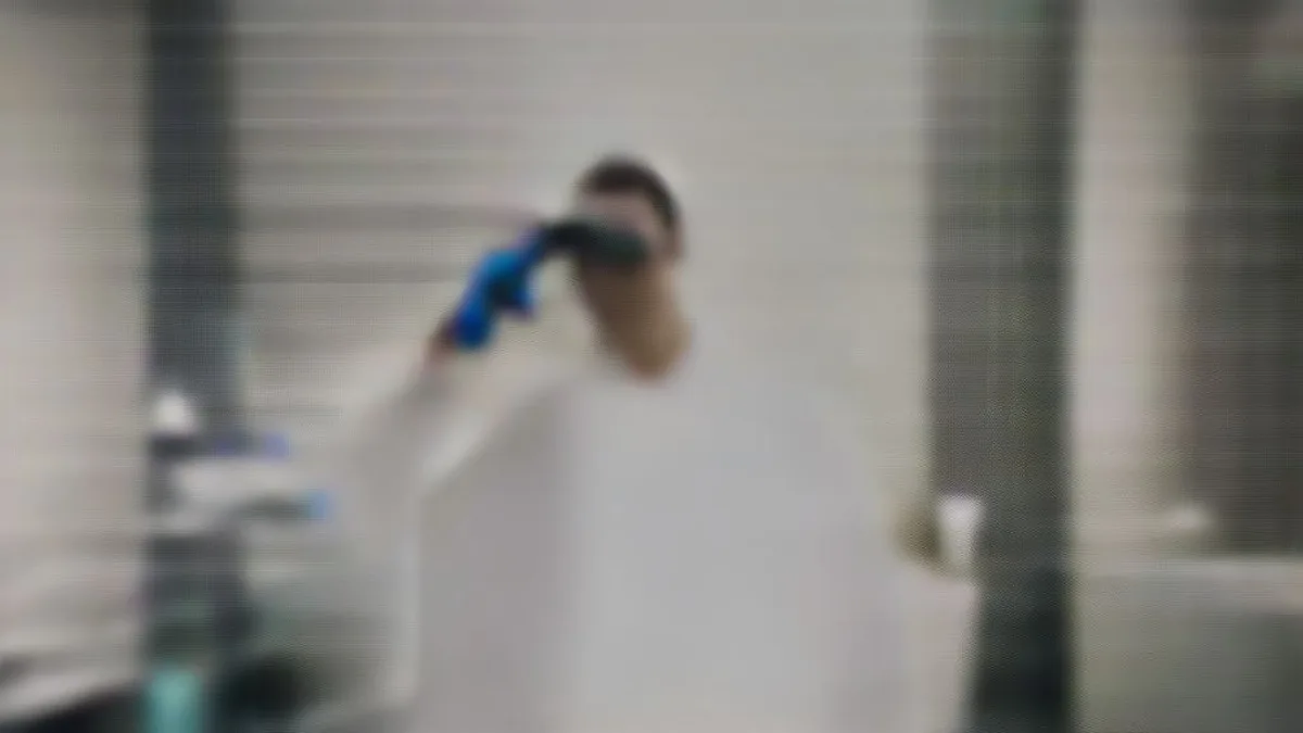 A clinical laboratory scientist working with specialized equipment in a modern biopharmaceutical research setting.
