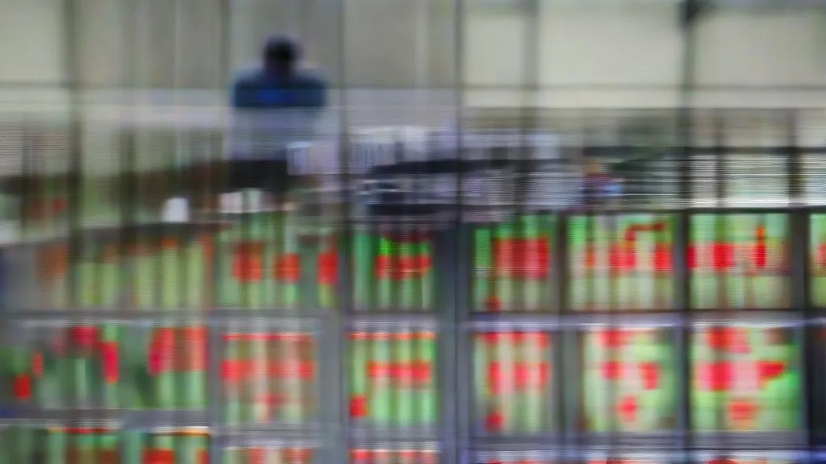 Financial trader looking at multiple computer monitors showing abstract market charts during an active trading session.