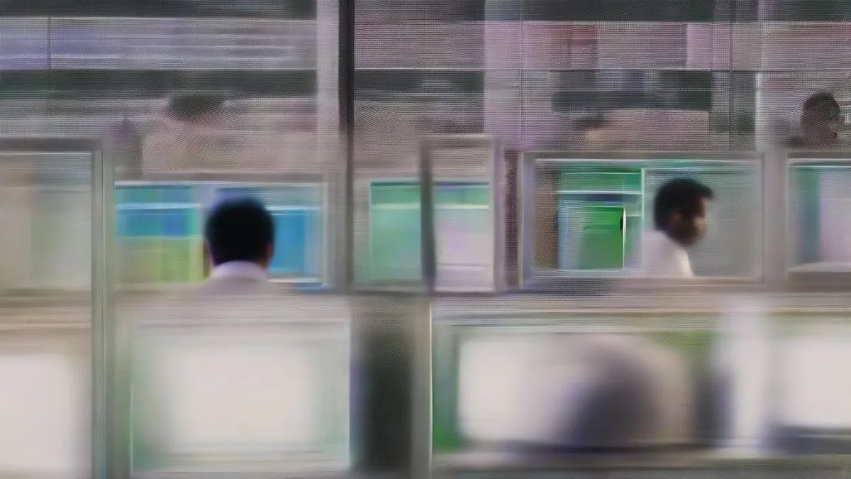 A financial trader sitting at a multi-monitor trading workstation in an institutional dealing room