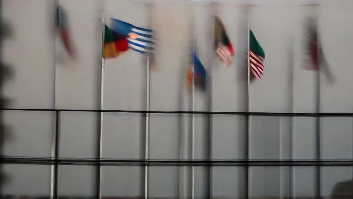 Exterior view of the United Nations headquarters with international flags and diplomats on the plaza