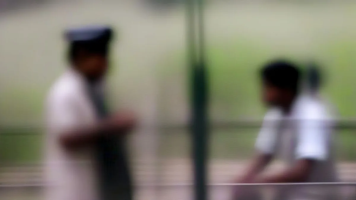 Police officers speaking near the exterior gates of an educational institution in southern India
