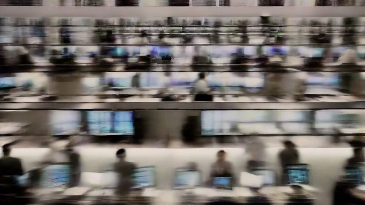 Traders working at multi-monitor desks on an active financial market trading floor.