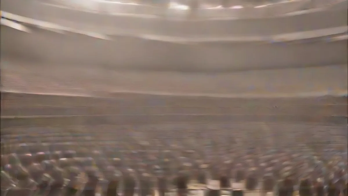 A campaign rally stage with a microphone podium under bright arena lights with a blurred audience in the background.