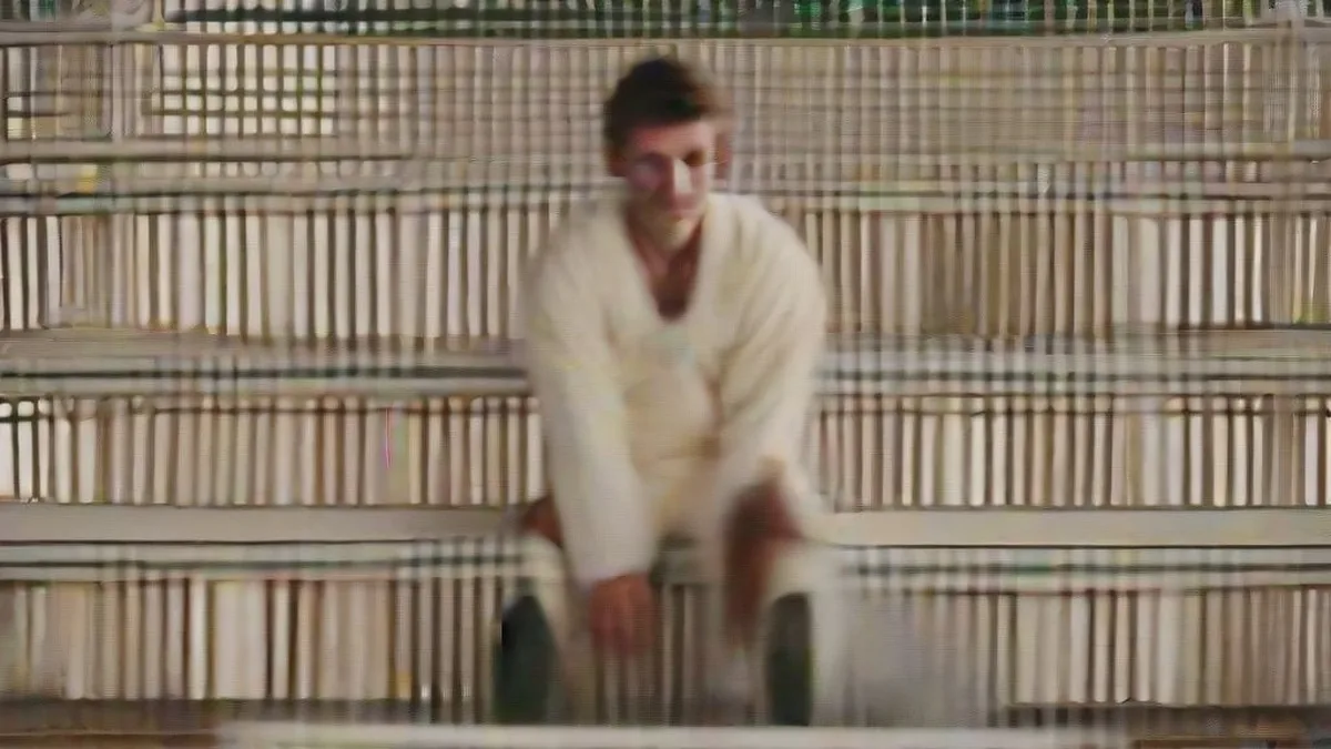 A cricketer in Test whites seated on a pavilion bench looking reflective after a match