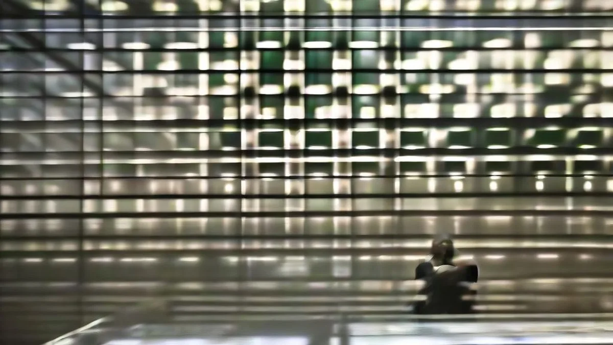 A financial trader analyzing market data on multiple computer screens on an institutional trading floor.